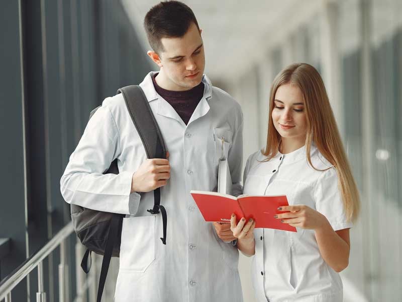 Estudiantes de odontología revisan apuntes en una libreta roja