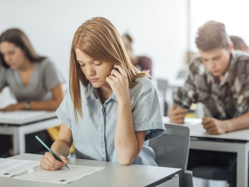 Estudiante resolviendo un examen de admisión en un salón de clases, preparándose para ingresar al bachillerato de la UNAM en 2025.