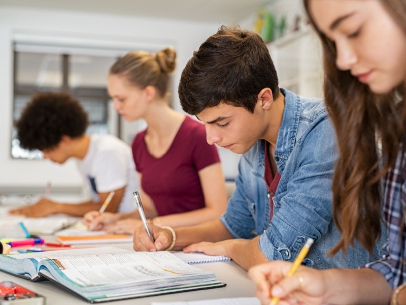 Jóvenes estudiantes trabajando en equipo en actividades académicas, preparándose para el examen de ingreso a la UNAM.