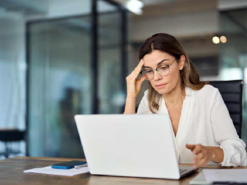 Mujer de negocios madura con expresión preocupada y fatigada, representando el impacto del síndrome del impostor en profesionales experimentados.