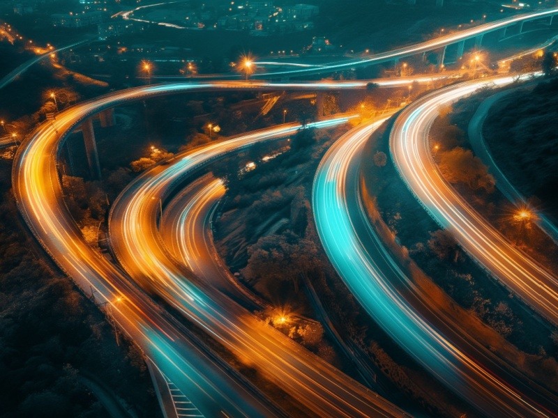 Fotografía aérea de carreteras urbanas iluminadas con luces de tráfico, representando planificación urbana y movilidad eficiente.