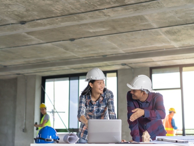 Arquitectos e ingenieros con casco en una obra en construcción, colaborando y discutiendo sobre el progreso del proyecto.