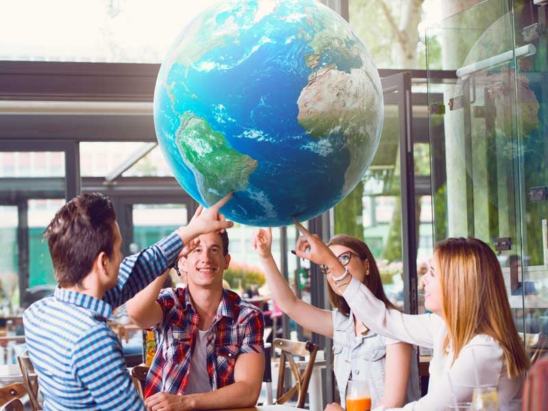 Estudiantes trabajando juntos con un globo terráqueo mientras estudian lenguas extranjeras y culturas globales en México.