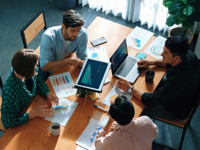 Vista superior de personas de negocios discutiendo ideas, representando el trabajo en equipo y la delegación de tareas en una reunión de colaboración.