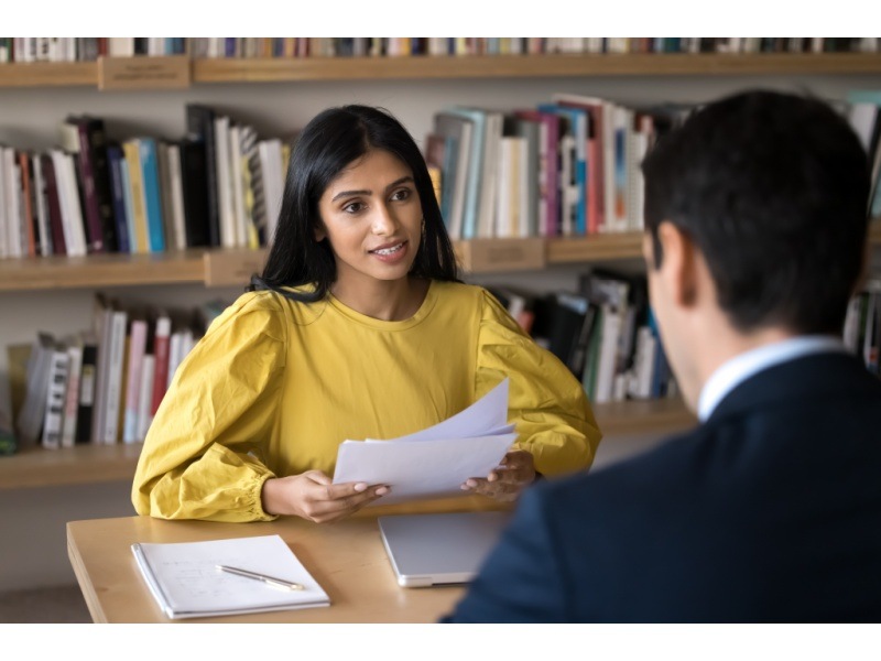 Reclutadora entrevistando a recién egresado con expresión amable y profesional