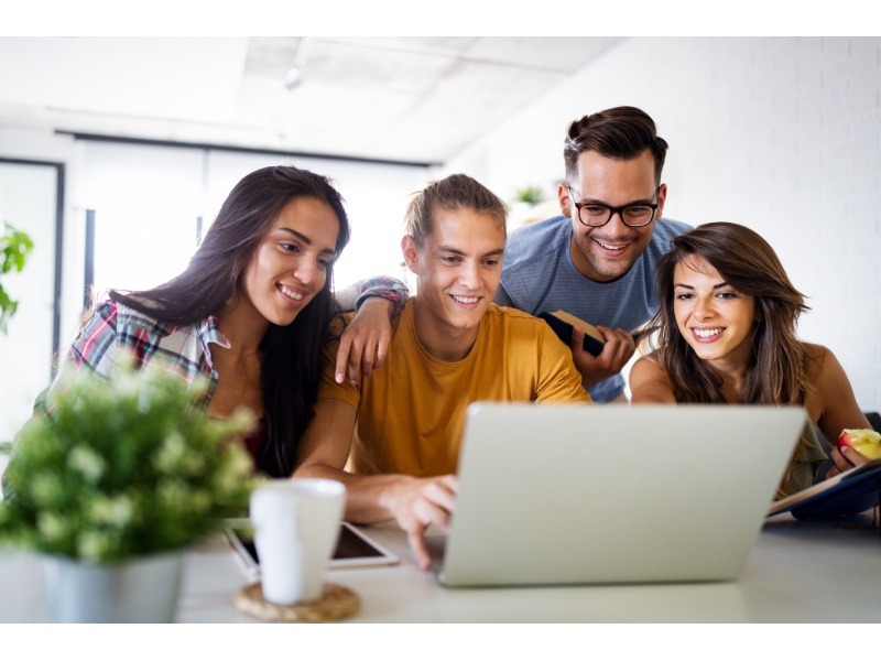 Jóvenes colaborando en equipo en un proyecto universitario, desarrollando habilidades blandas y de liderazgo