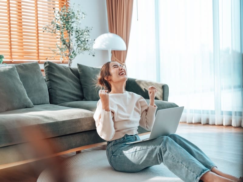 Estudiante celebrando logro académico mientras estudia una licenciatura en línea desde su hogar