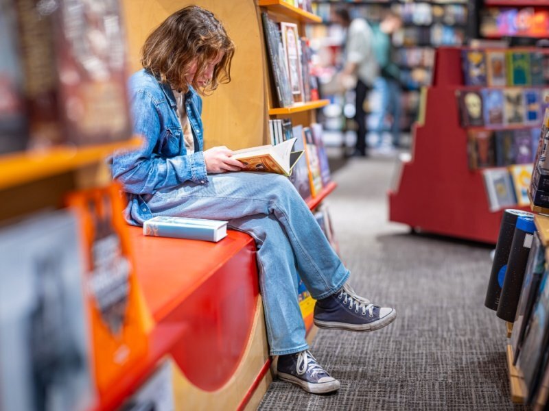Adolescente leyendo en librería, fortaleciendo el hábito de estudio y pensamiento crítico antes de entrar a la universidad