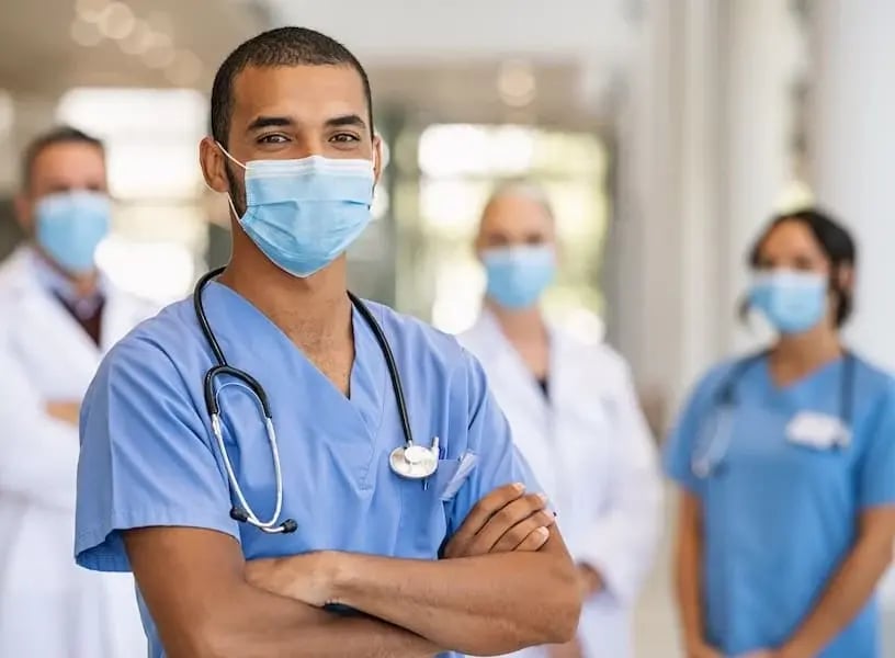 Enfermero con bata azul y cubrebocas en hospital – Representación del rol esencial de los enfermeros en el sistema de salud en México.
