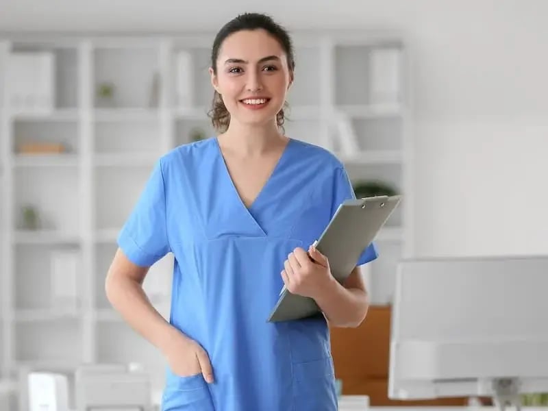 Estudiante de enfermería con uniforme azul y portapapeles – Formación profesional en enfermería con enfoque en atención médica y desarrollo académico.