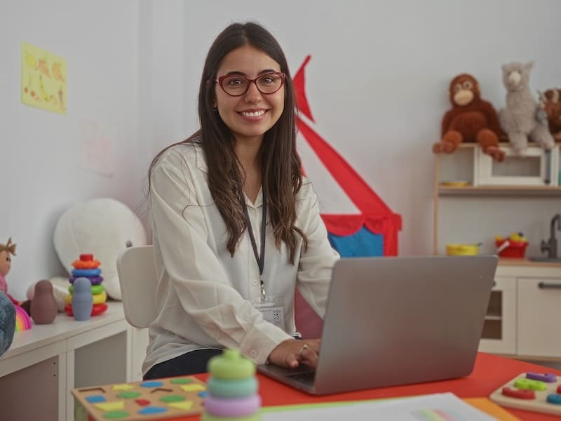 Profesional de Pedagogía trabajando con recursos educativos y tecnología para el aprendizaje infantil.